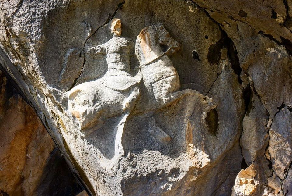 Termessoslu bir kahraman silahlarını kuşanmış atının üstünde olarak bir kayaya kabartması yapılmış. Hemen yanında kendisini onurlandırmak için yapılmış bir kaya mezarı var.